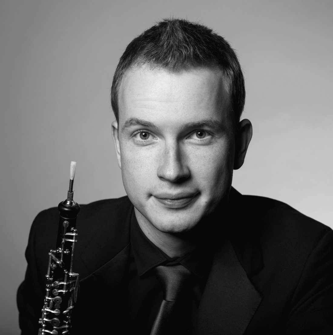 Black-and-white portrait of Aleh Remezau holding his oboe